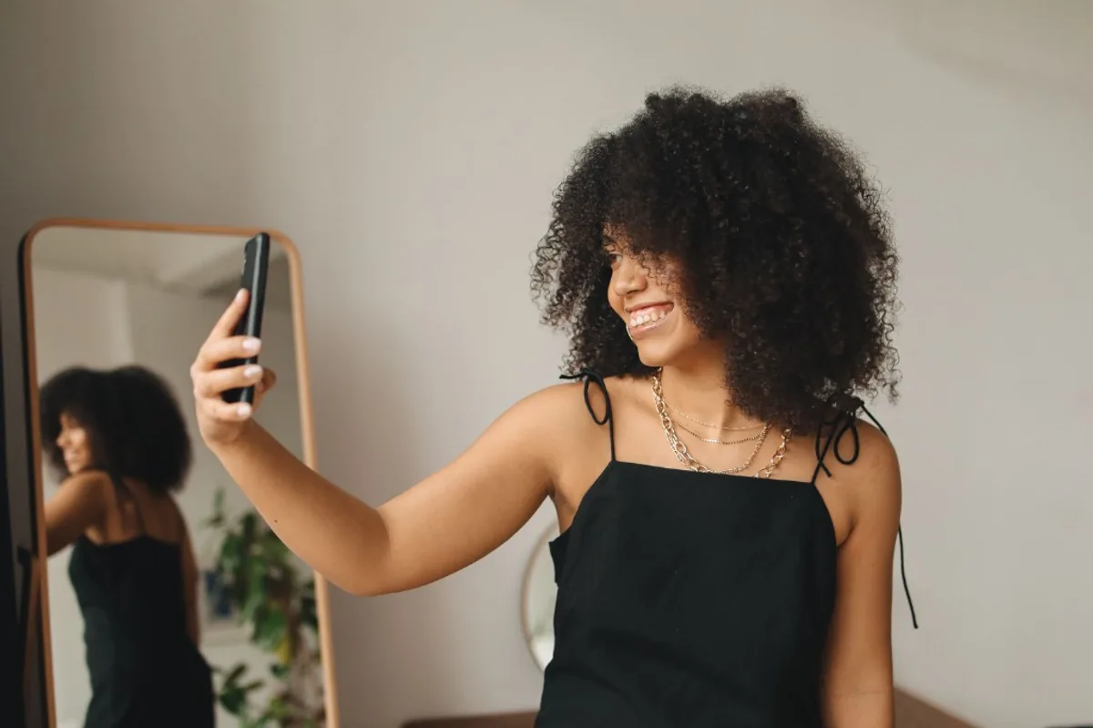 Mulher tirando selfie pelo celular para verificação de perfil no aplicativo Bebaby