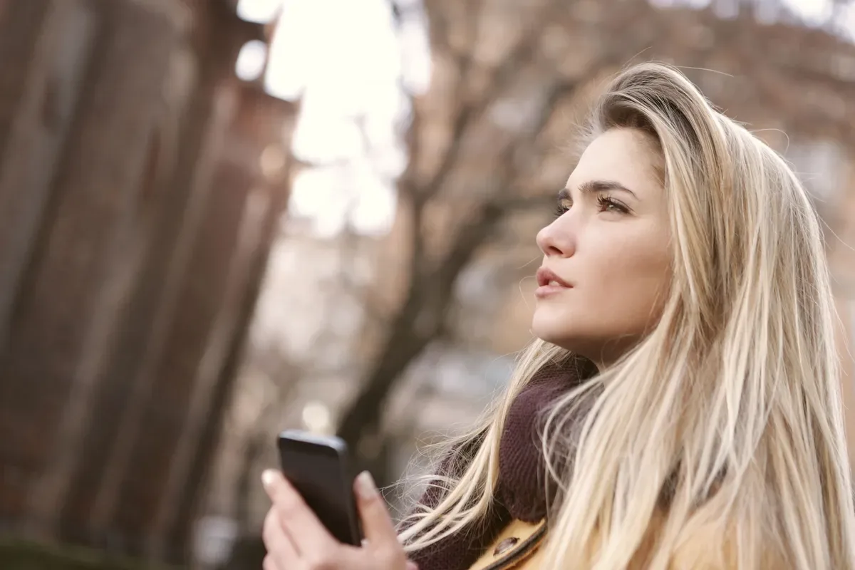 Jovem com celular na rua, expressão pensativa, ilustrando a decisão de entrar no universo sugar
