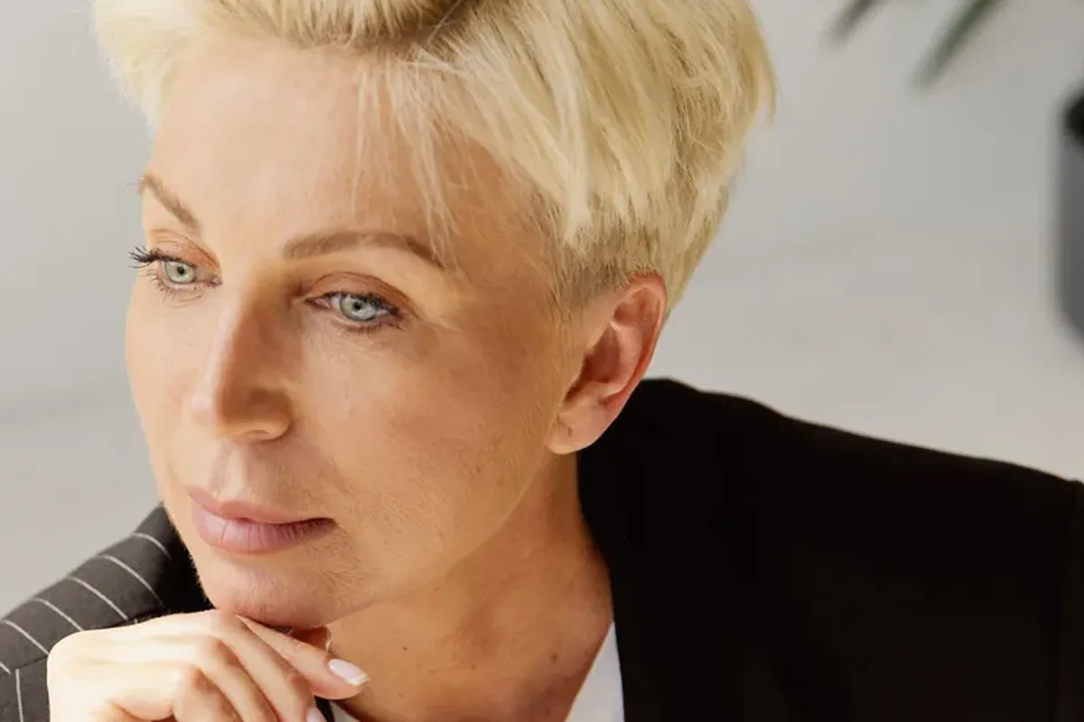 Mulher madura de blazer com expressão pensativa, ilustrando o perfil de sugar mommy