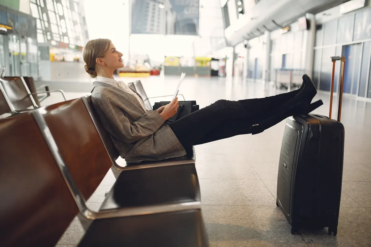Jovem sentada no aeroporto com mala e cartão de embarque, ilustrando viagem em relacionamento sugar